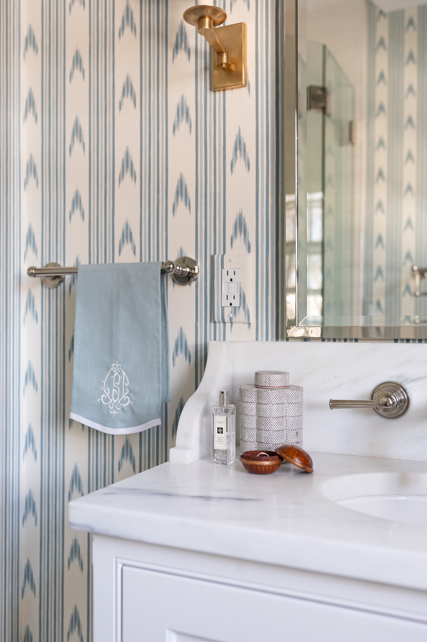 Image of bathroom with marble countertops and blue wallpaper.