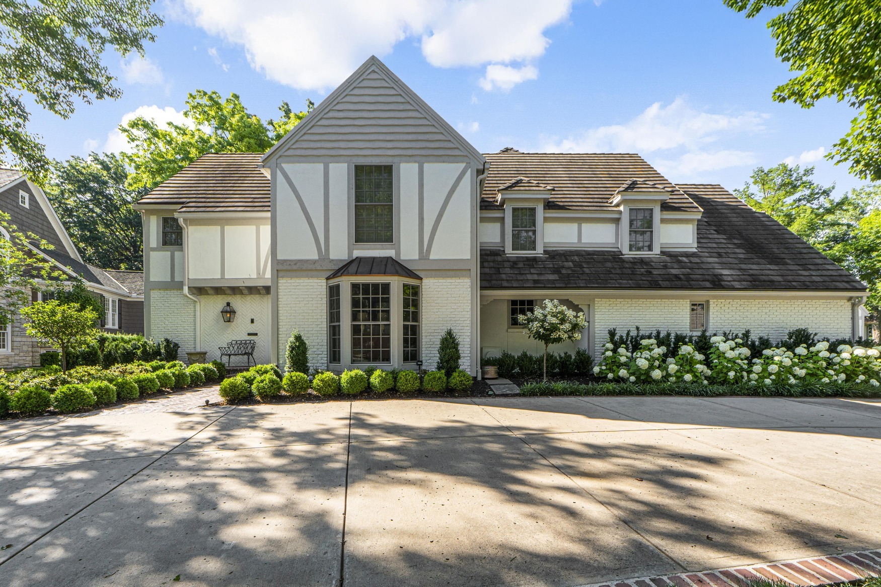Facade of a renovated home featuring a bay window and landscaping surrounding the pavement.