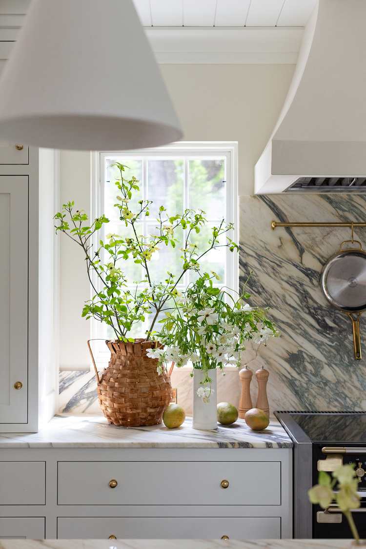 First half of a range elevation highlighting the natural stone backsplash, flat-panel drawers, and bright natural light.