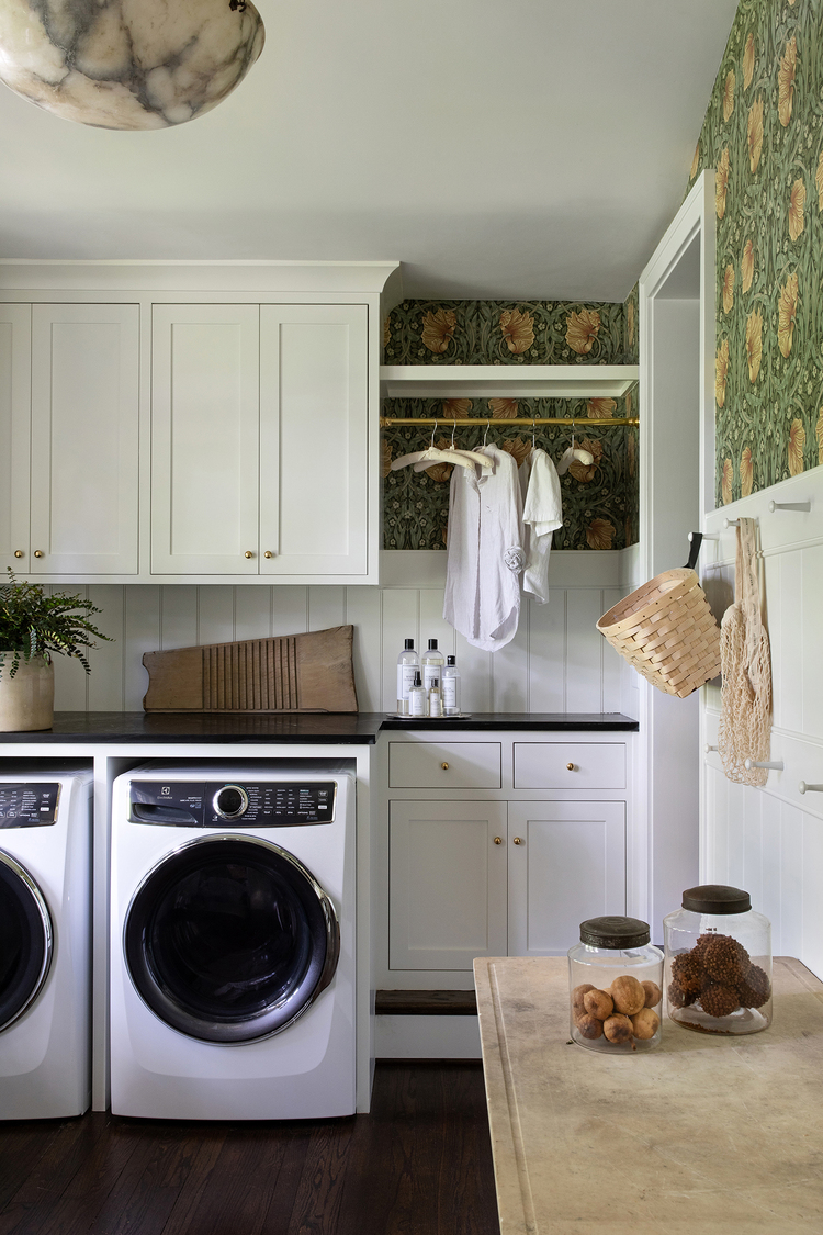 Laundry room cabinet run featuring custom storage niches above and below the counter. White V-groove paneling pairs with green William Morris wallpaper to create visual interest.