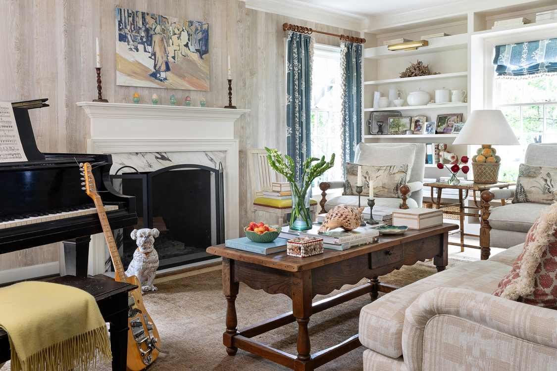 A marble fireplace with white molded mantel is the centerpiece to this transitionally styled living area, framed by a grand piano on the left, and recessed shelving on the right. 